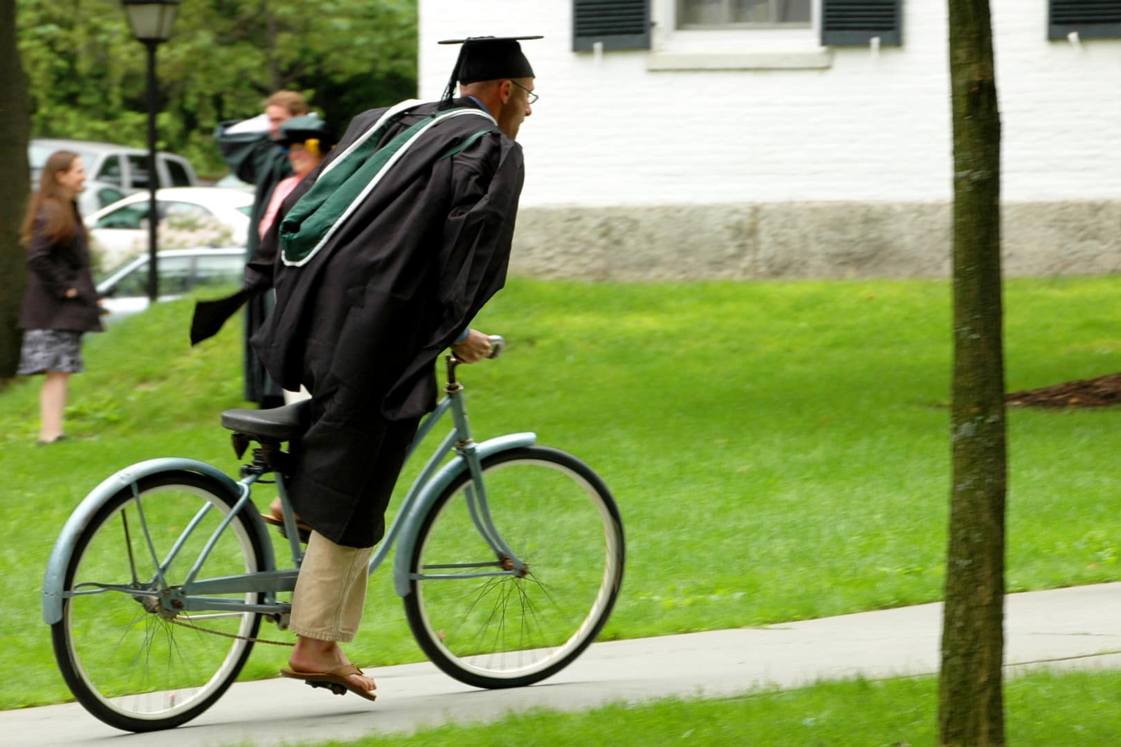 A recent graduate rides a bike across campus.